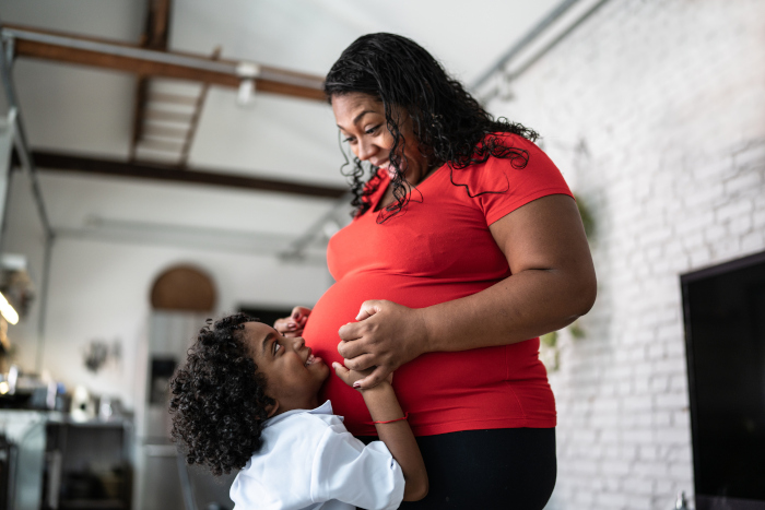 Pregnant mother and little girl smiling