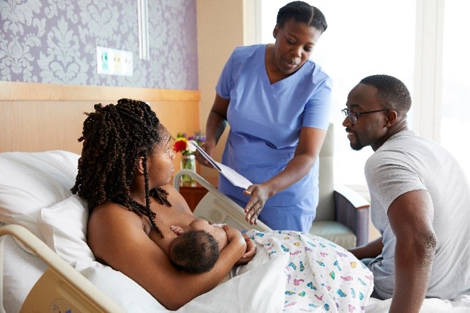 A mother and father embracing while the mother breastfeeds. 