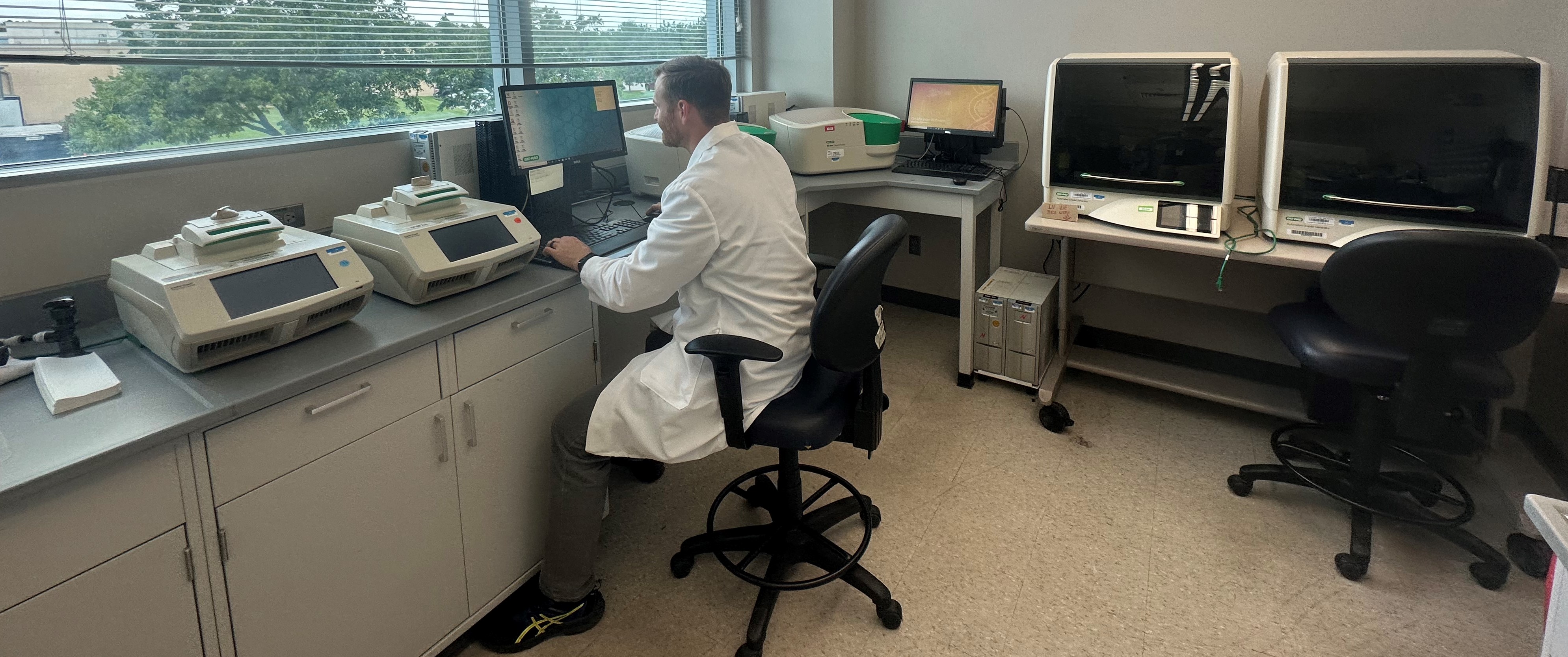 Lab Tech in front of instruments in room with windows