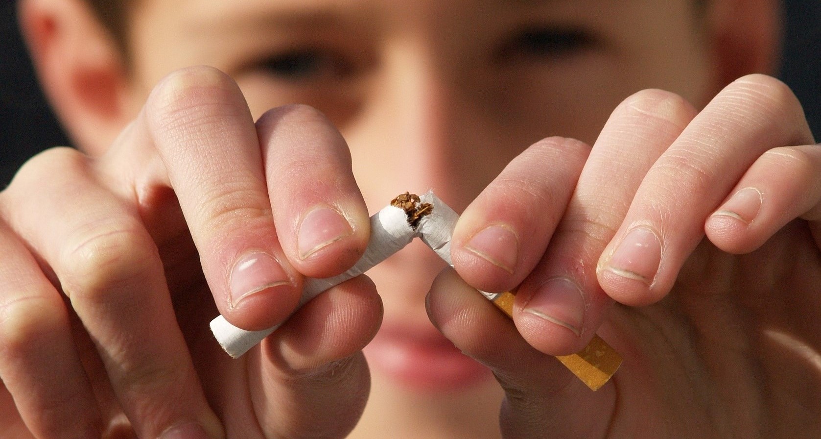 Person breaking a cigarette in half