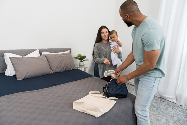 A mother holding a child and a father packing a breast pump.