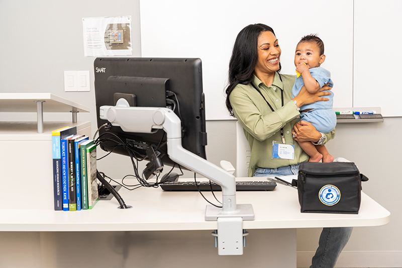 A woman holding an infant at work. 