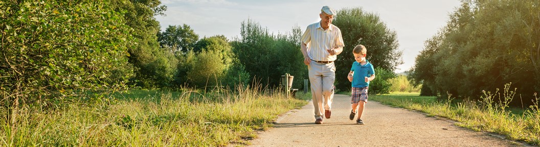 "Elderly man and boy walk down a path outside"