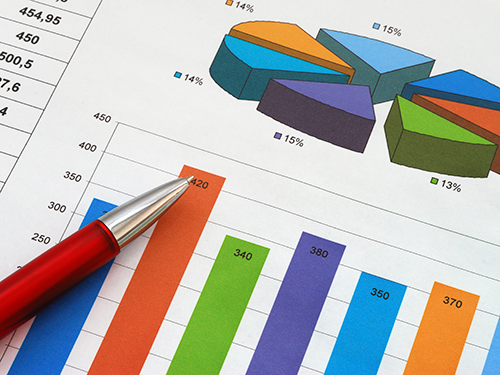 A pen laying on printed charts and graphs.